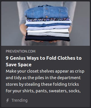 By Prevention. A photo o’ a blurry woman holding a stack o’ folded blue clothes.